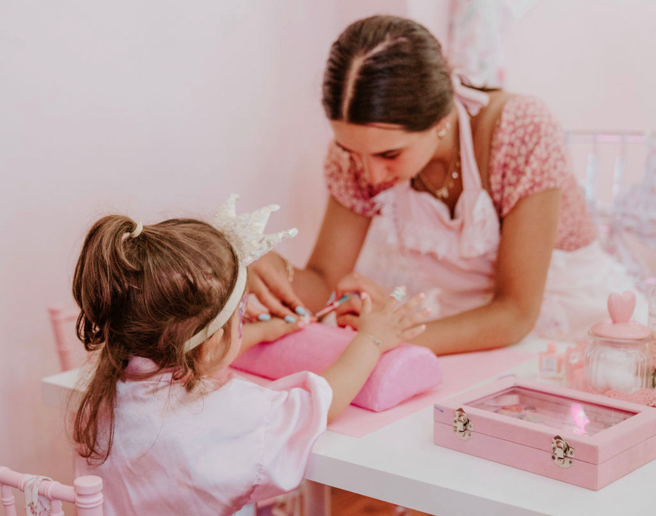 little girl receiving a manicure with glitter
